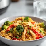 High protein crock pot chicken with vegetables and quinoa in a white bowl on a bright, modern kitchen counter.